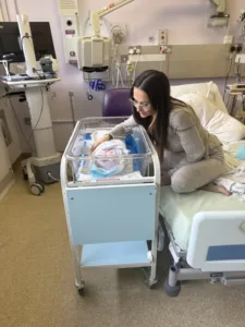 Lauren next to Kitty's cool cot, she is gazing down ant her and smiling.