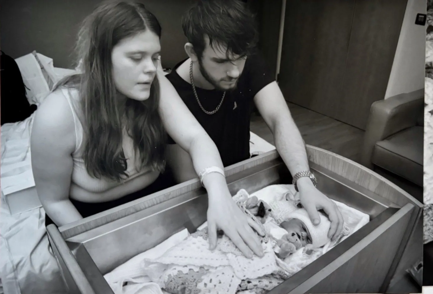 Maddie and Corey-Jack looking at Elsie in her cot. Both their left hands are stroking her.